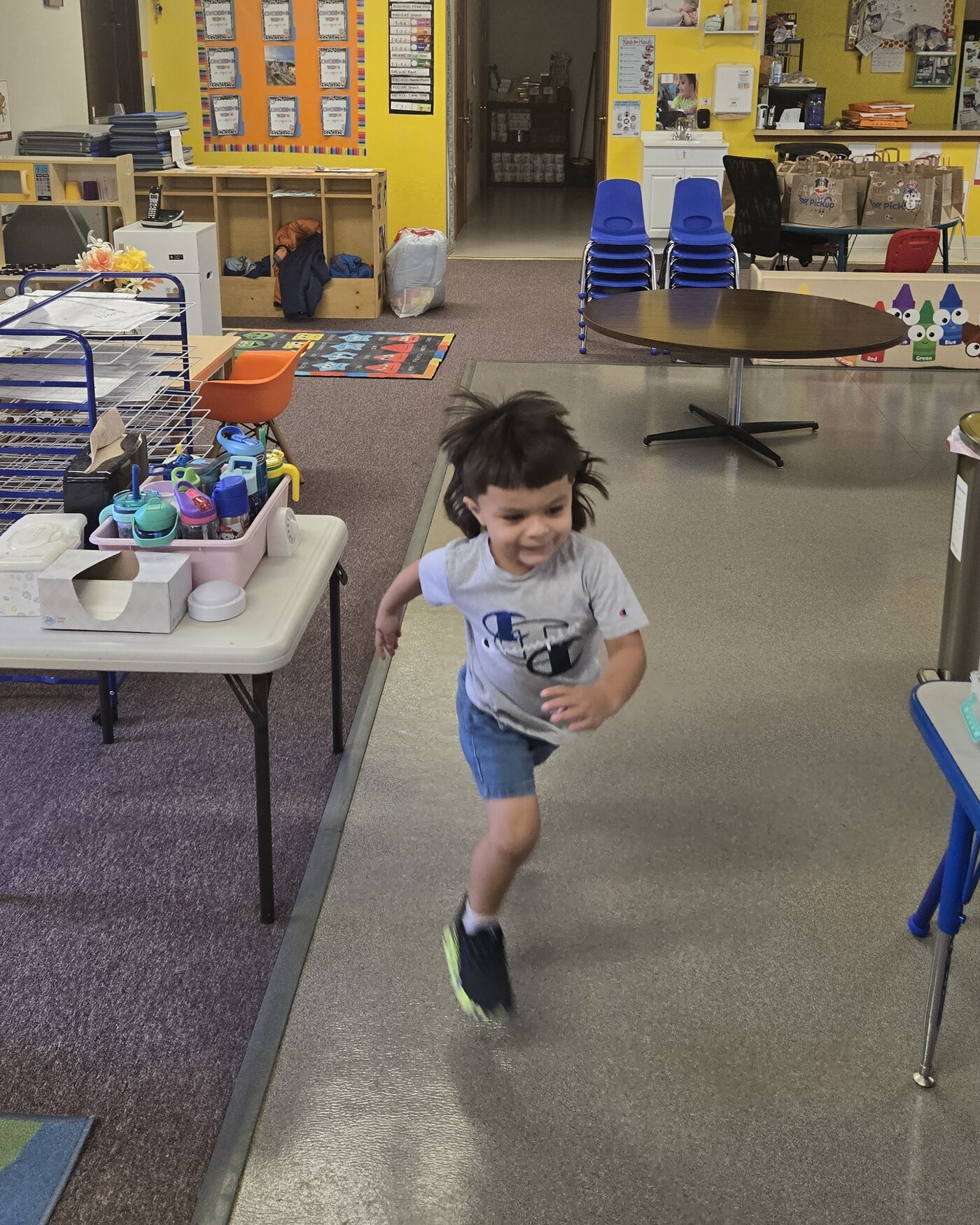 A preschooler running and smiling through the Apple Valley preschool room