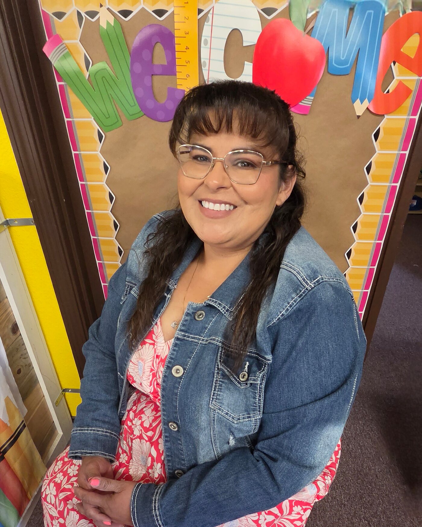 Angelica Sanchez, owner of Apple Valley Childcare and Preschool, smiling in front of the welcome board