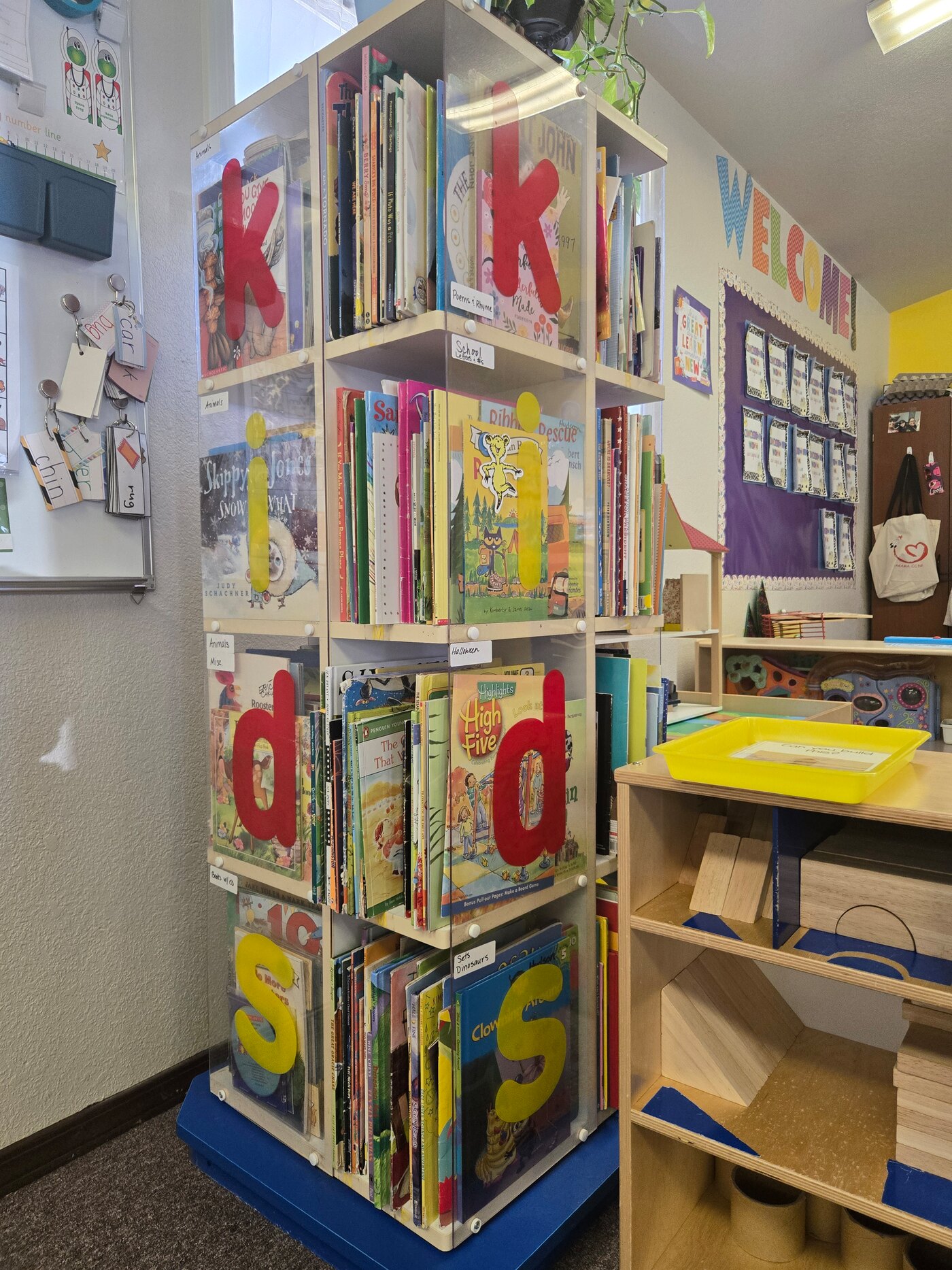 The picture-book carousel and block shelves in the Apple Valley pre-K room, with the welcome board behind